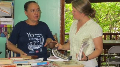 Maria Anela, the director of the library, sorts recently donated books with Becky.