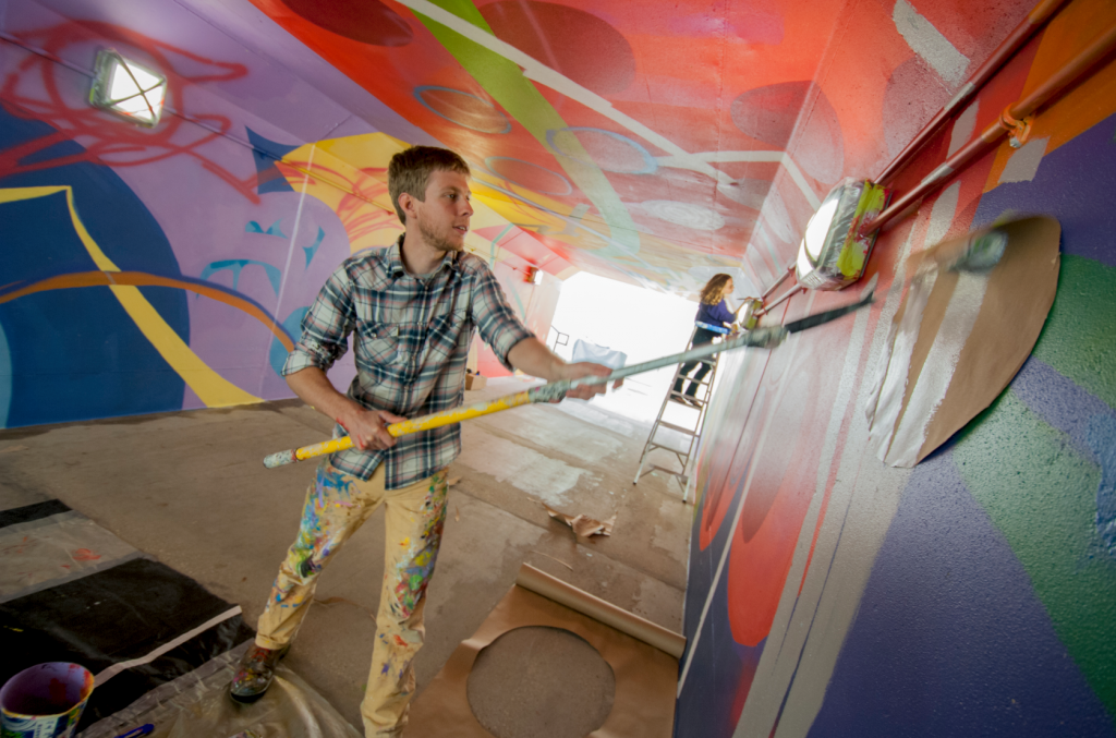 Noah Yoder painting underpass mural