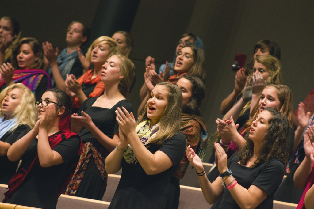 The Goshen College Women’s World Music Choir performs during the homecoming weekend celebrations. During performances, members wear vibrantly colored scarves and go barefoot as a way to feel connected to the earth and to women around the globe. (Photo by Alia Munley)