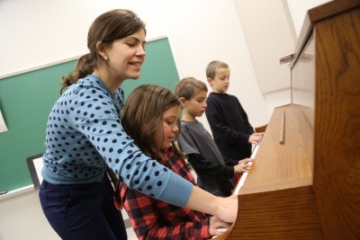 Woman teaches children how to play the piano