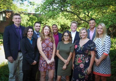 Students in formal clothing posing together in two rows, smiling