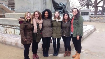 Six Women in winter jackets posing together, arms wrapped around each other