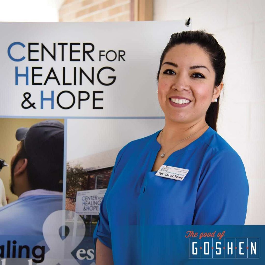 Woman in a blue shirt smiling in front of a Center for Healing and Hope sign