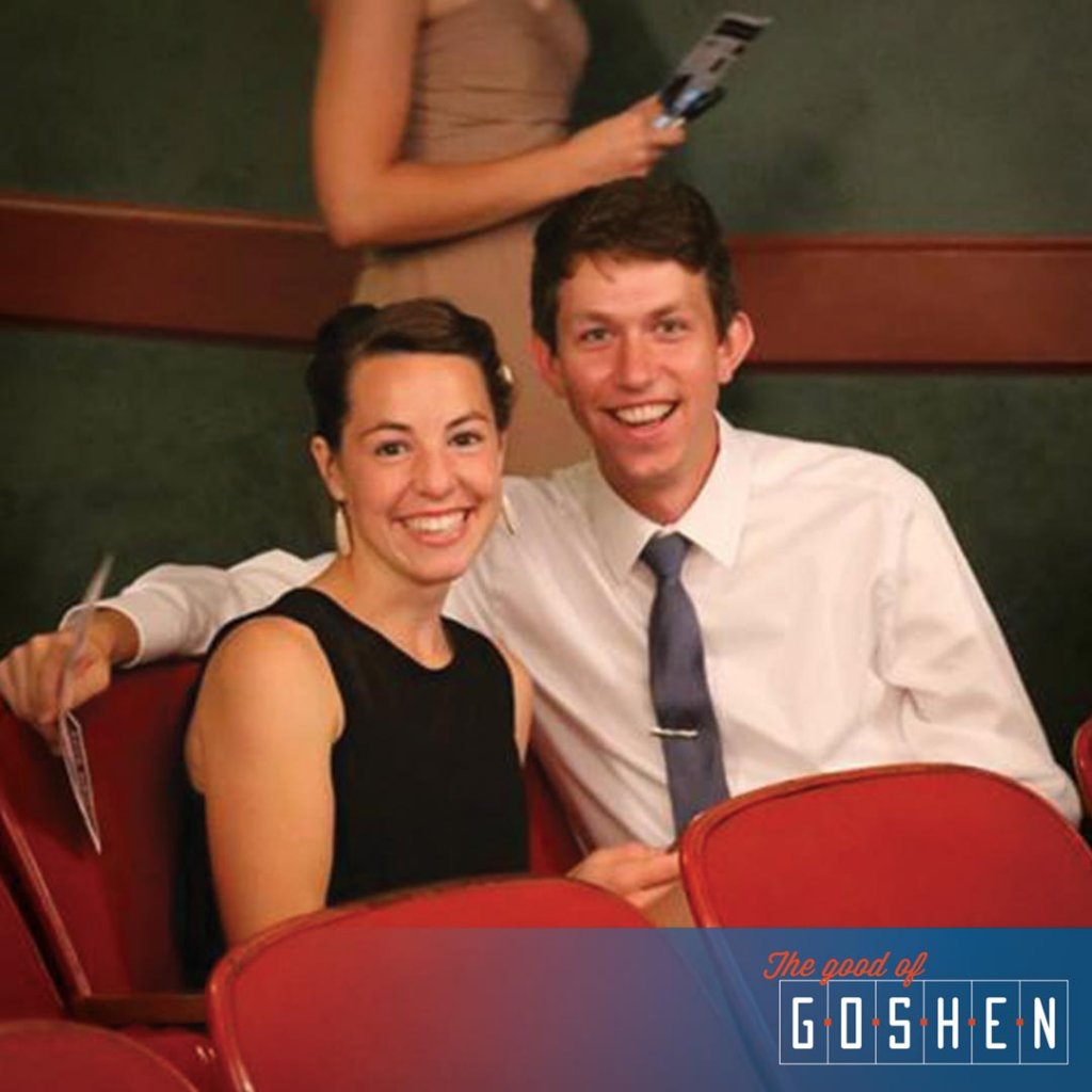A couple sitting together in red theater chairs