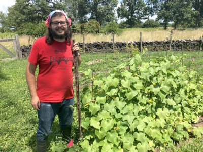 Stephen Lowe with a cucumber plant he trellised during the 2019 Agroecology Summer Intensive.