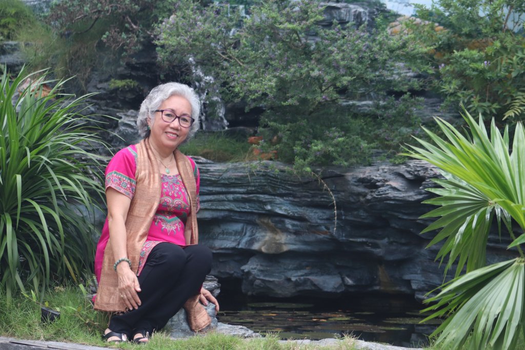 Woman in a pink shirt posing by a pond