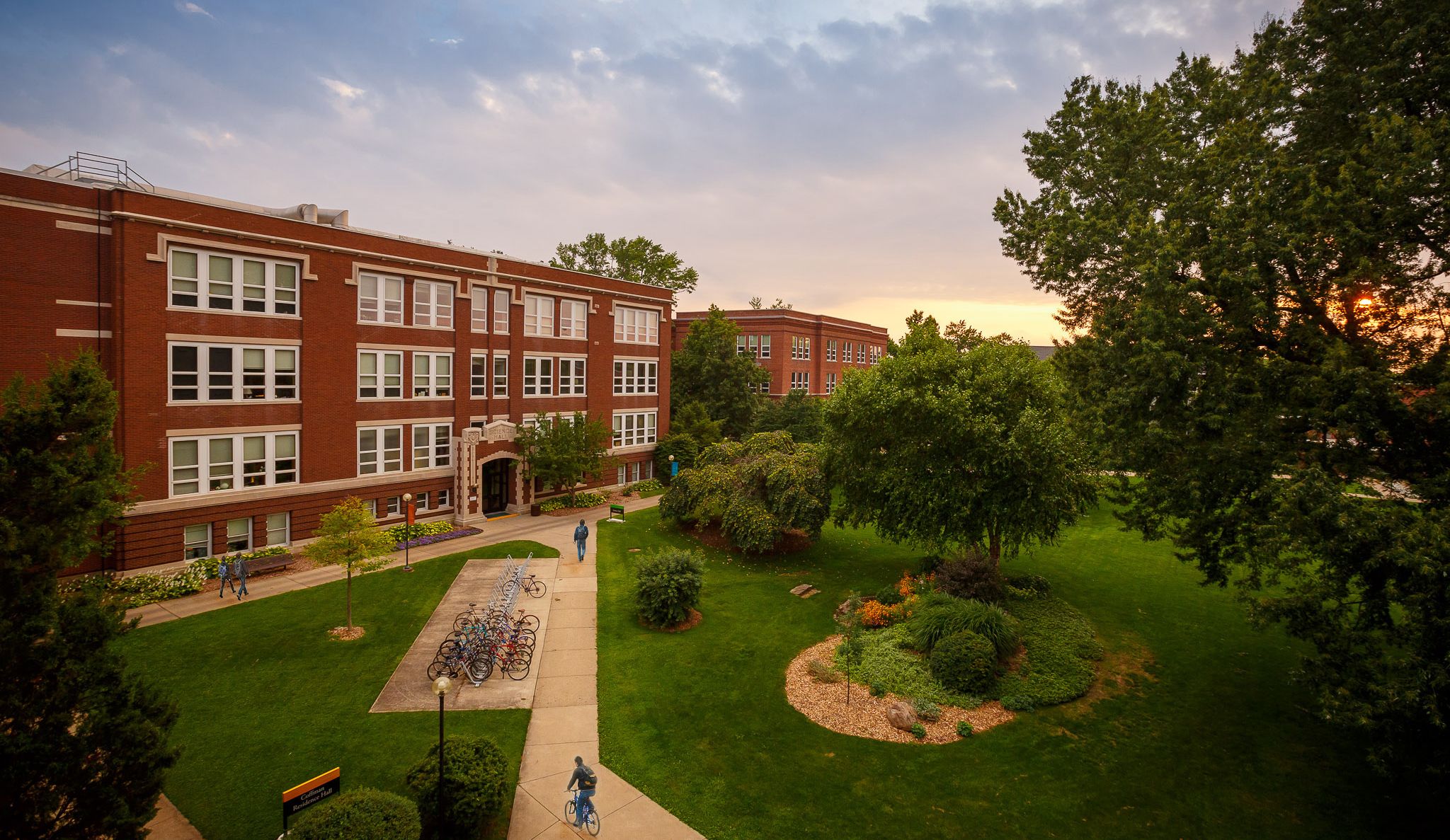 Students walking and bicycling by Goshen College's Science and Administration Buildings