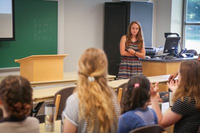 Student in a striped dress giving a presentation