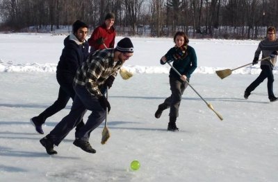 Students in winter clothing playing broom ball