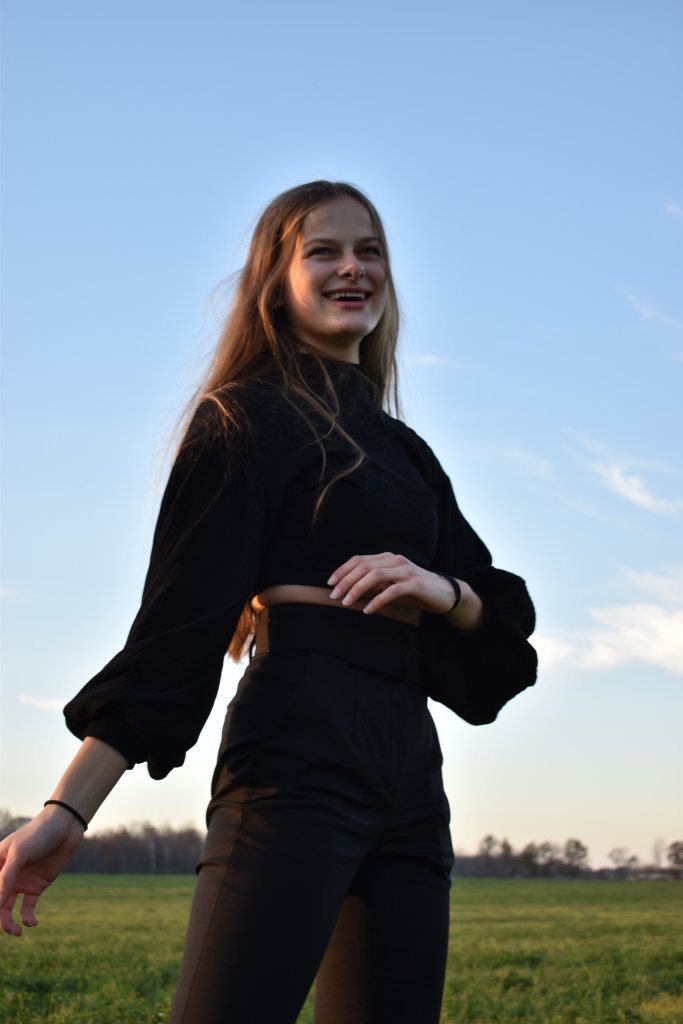 Woman in a black shirt and pants smiling in a field