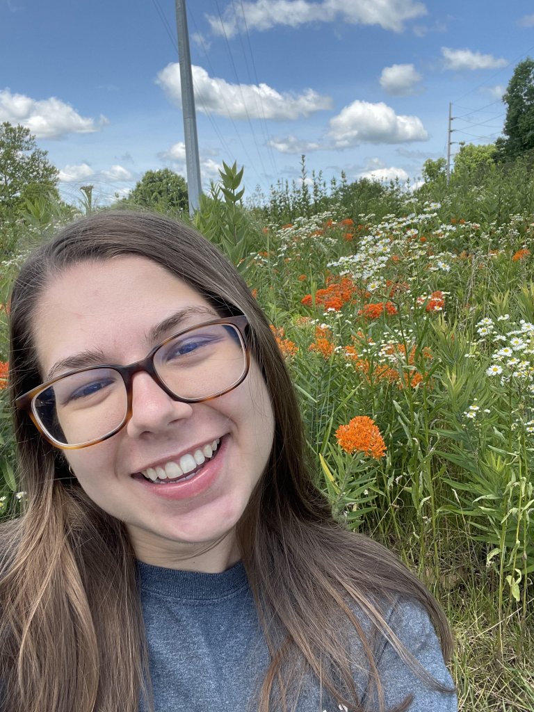 Woman wearing glasses smiling in a field of wild flowers