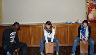Camilo Ballumbrosio teaches Lauren and Becca how to play the cajon.