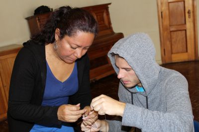 Eliana helps Alan with his bracelet.