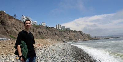 Jake checks out the rocky beach. In the background: high-rise apartment buildings in the Miraflores district.