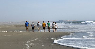 Goshen College men stroll down the beach.