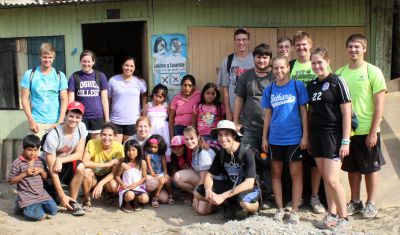 Goshen College students pause for a group photo with Corpusa Villavicencio Zela and her children in the Chavín de Huántar neighborhood of Villa El Salvador.