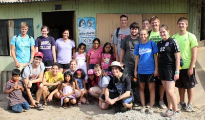 Goshen College students pause for a group photo with  Corpusa Villavicencio Zela and her children in the Chavín de Huántar neighborhood of Villa El Salvador.