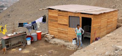 A mother of two stands beside her newer home in Puente Piedra.