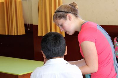 Emma shows a string game to a boy.