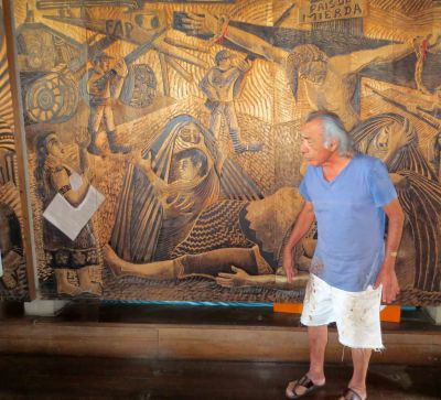 Peruvian artist Victor Delfin poses in front of his huge wood carving depicting atrocities on both sides of the Shining Path war.