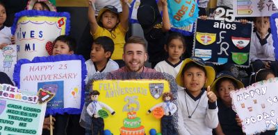 Lane holds a "Happy Anniversary" poster with his students back in the gym.