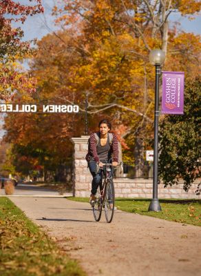 Student riding a bike on the Goshen College campus.