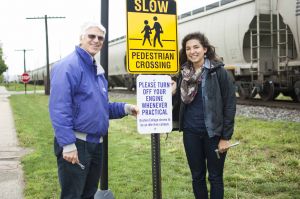 Glenn Gilbert (left), sustainability coordinator at GC, and Gretchen Geyer (right), a senior from Parnelll, Iowa, who initiated the project, pose with the newly-installed "no idling" sign on the GC campus.