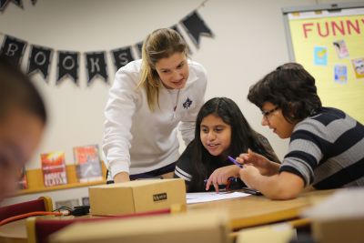 Goshen College junior Megan Gerke helps seventh grader Sam Smith and sixth grader Nayely Arellano with a coding problem. 