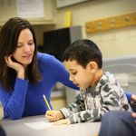 Student helping a child in a classroom