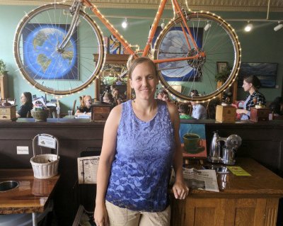 Women posing in front of a hanging bicycle at a coffee shop