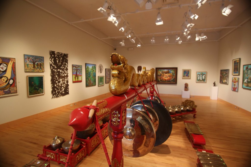 the Gamelan in the middle of an art gallery that is full of paintings on the wall.