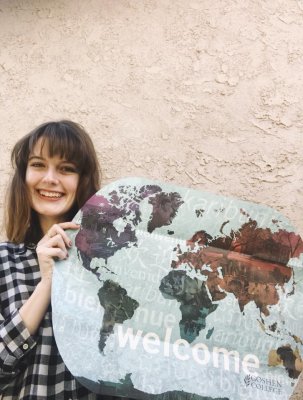 Woman smiling while holding a GC poster that layouts the world.