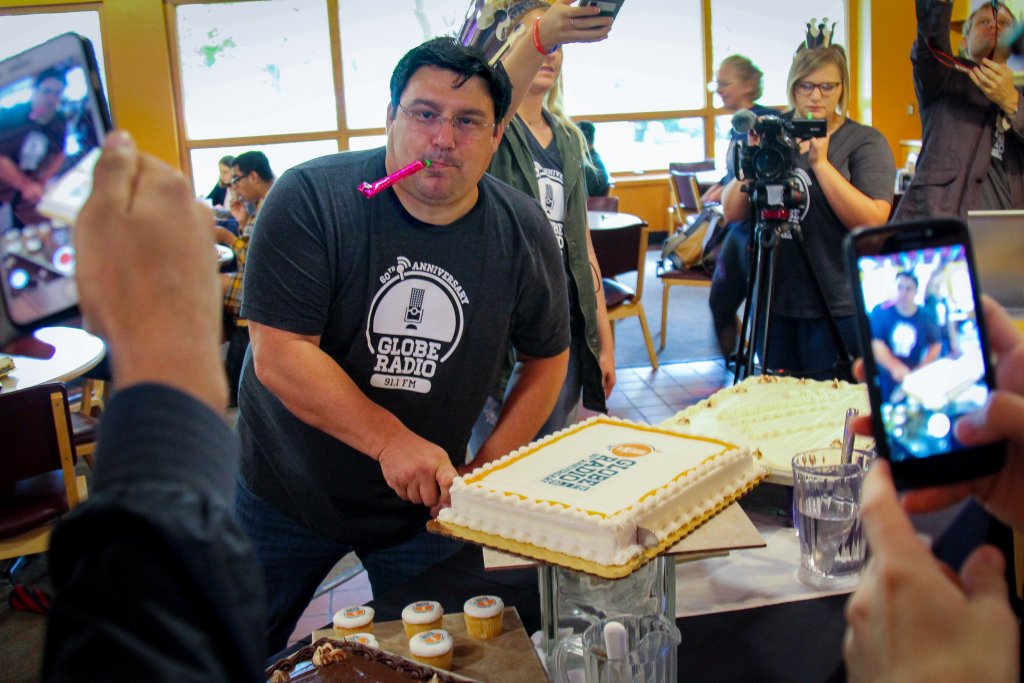 Professor Jason Samuel cuts cake while everyone around tries to capture the best shot on their cellphones.