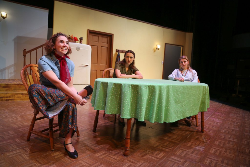 Three students acting while sitting at a table