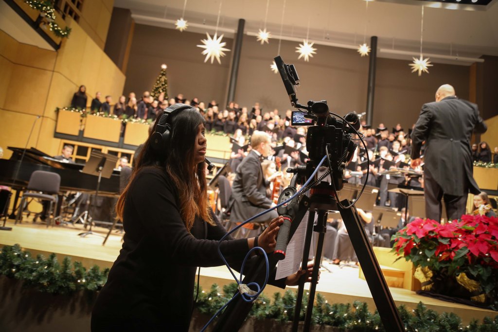 A female student recording a Choirs and Orchestra during a music performance