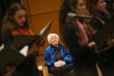 Alice Parker listening, with her eyes closed, to Women's World Choir sing a song.