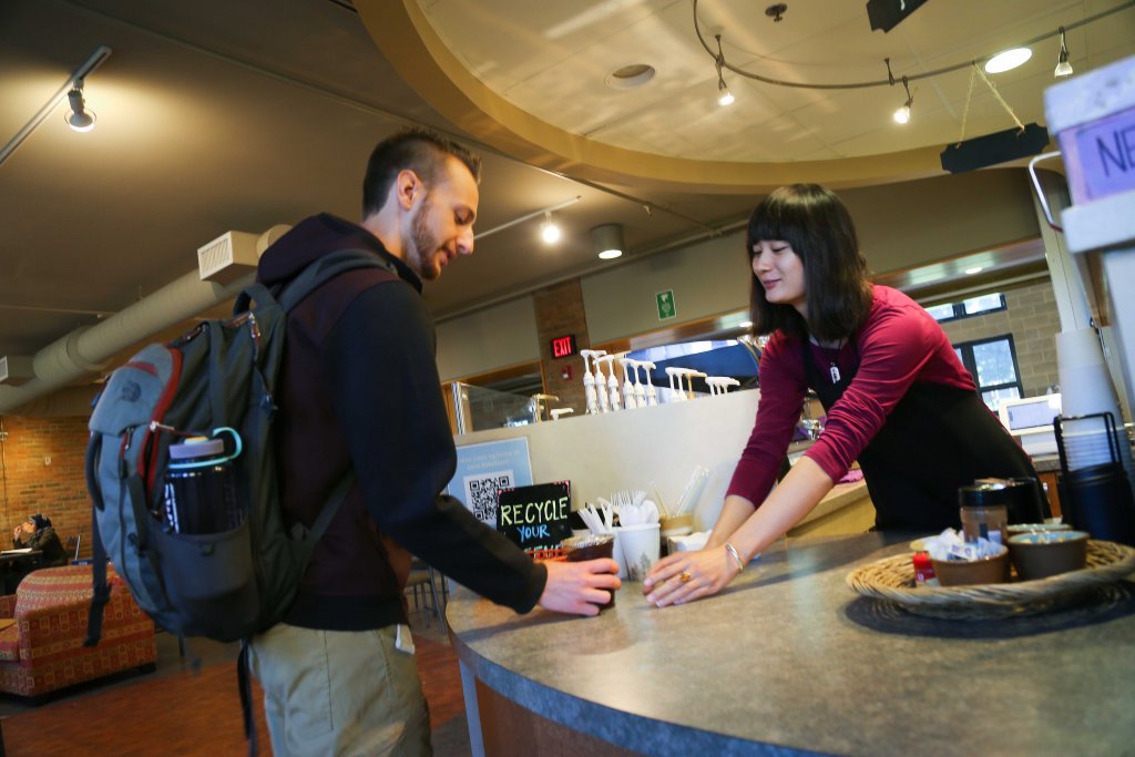 A student giving and a student receiving iced coffee at Java Junction.