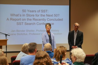 A woman and man in front of a projection that says "50 Years of SST: What's in Store for the Next 50?"