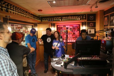 Multiple people from off campus touring the radio station while a student is working on the computer.