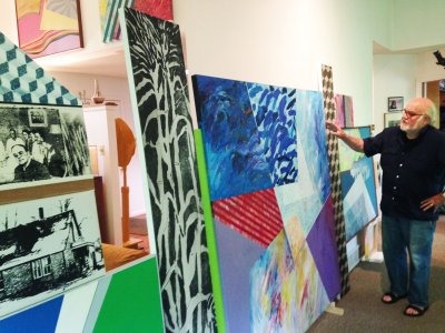 Man is pointing to large colorful paintings
