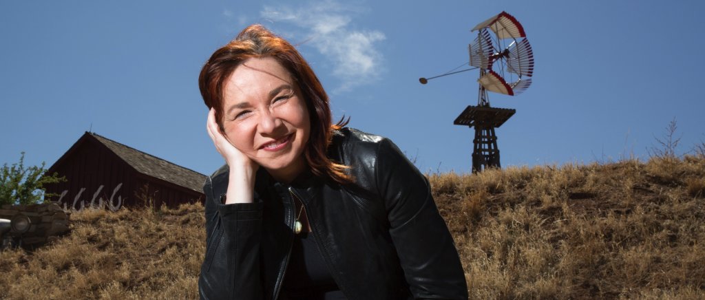 Woman with grassy hill and wind machine in the background