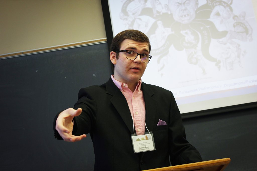 Male student presenting behind a podium while in a suit jacket