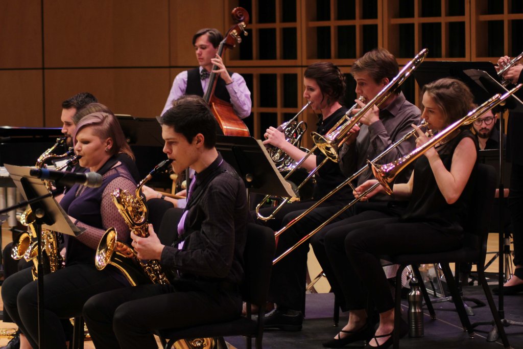 Jazz ensemble featuring people playing saxophones, trombones, french horn and upright bass