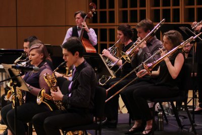 Jazz ensemble featuring people playing saxaphones, trombones, french horn and upright bass