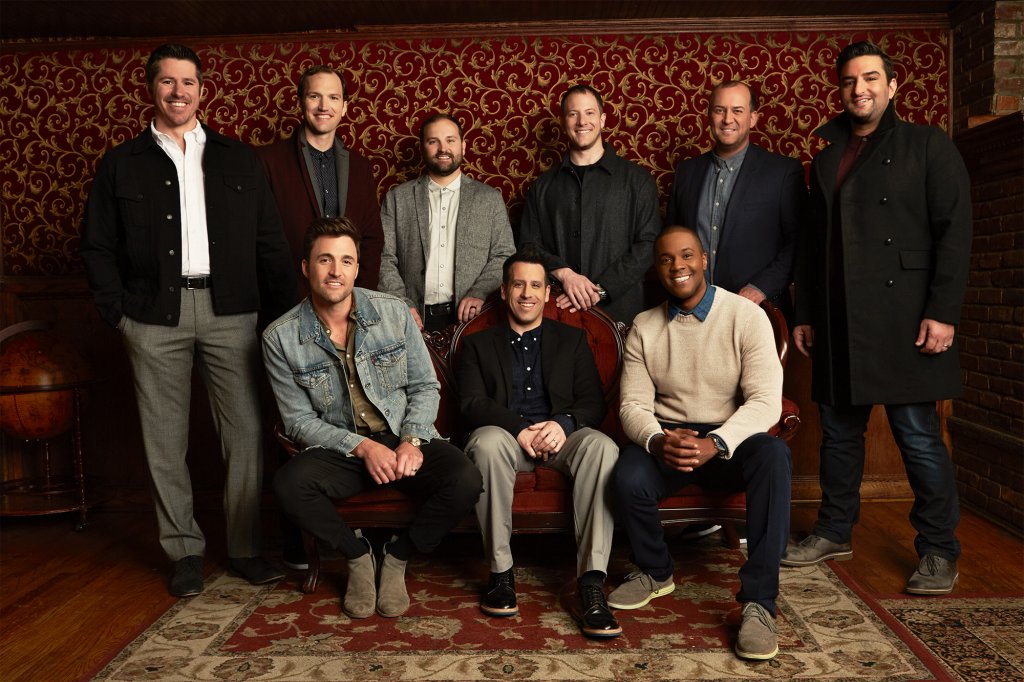 Nine men sitting and standing to pose for a picture while wearing business casual attire