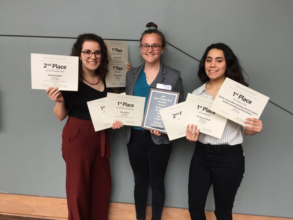 Three female students holding certificates and a plaque.