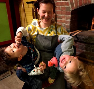 Woman wearing an apron and holding two young children in her arms