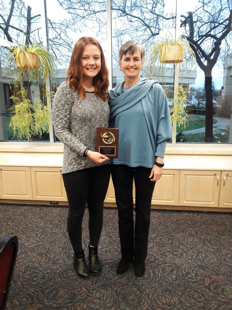 Two women holding a plaque between them