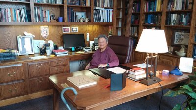 Geraldine Chan at a desk surrounded by bookshelves