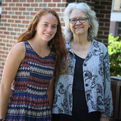 Two women standing in front of a brick wall